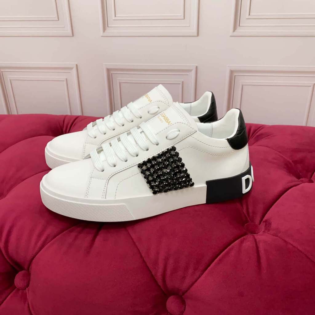 White Dolce & Gabbana sneakers Dolce & Gabbana Women Calfskin Portofino Vintage Sneakers with Black Crystal Embellishment - White & Black Product Description, displayed on a red cushioned surface