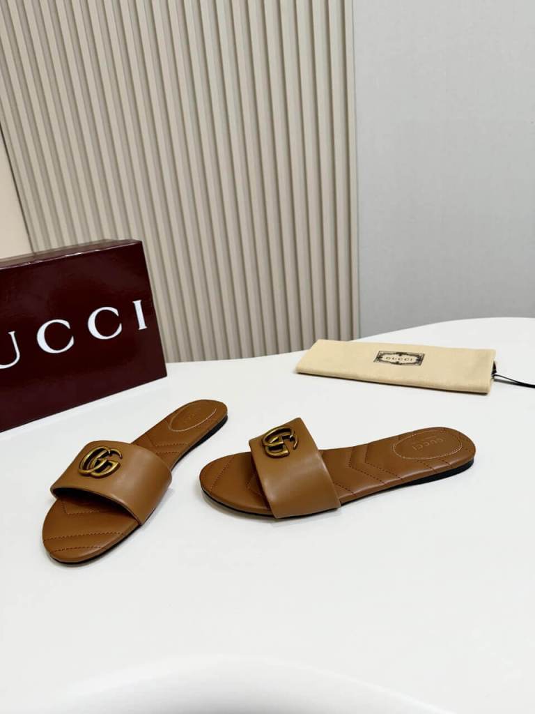a pair of Gucci Women's Double G slide sandal - Brown on a table