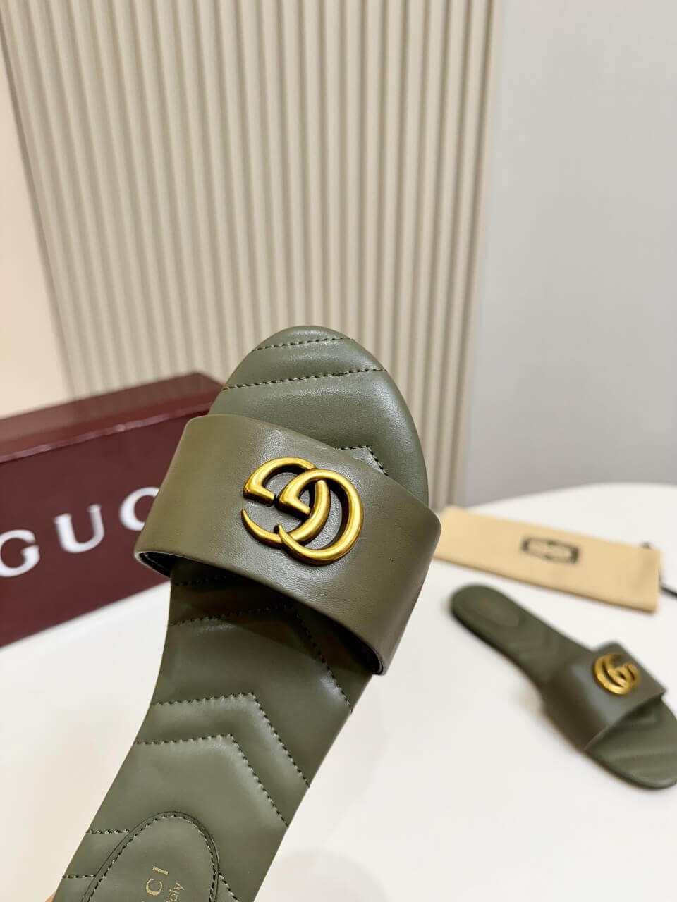 a pair of Gucci Women's Double G slide sandal - Olive Green on a table