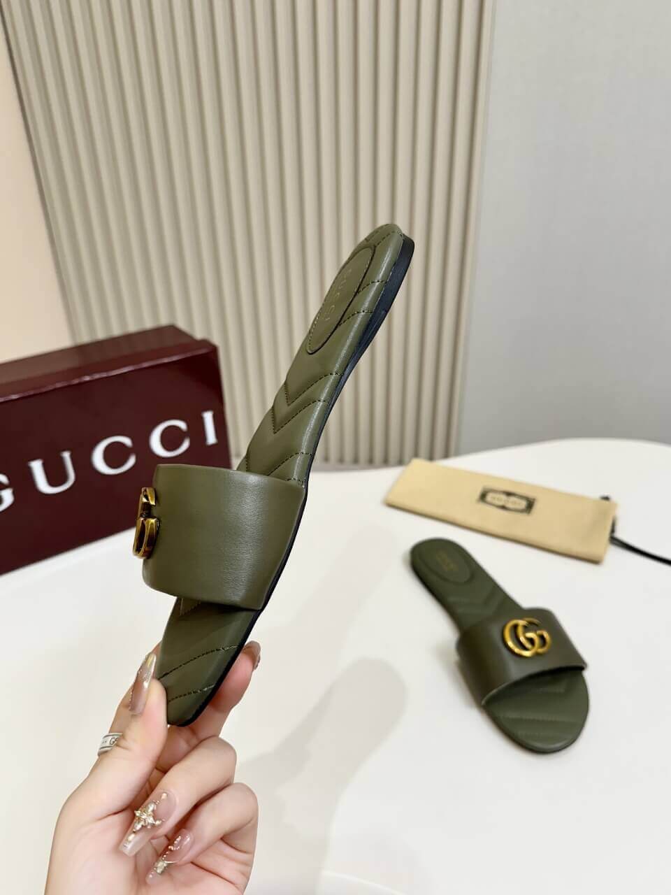 a pair of Gucci Women's Double G slide sandal - Olive Green on a table