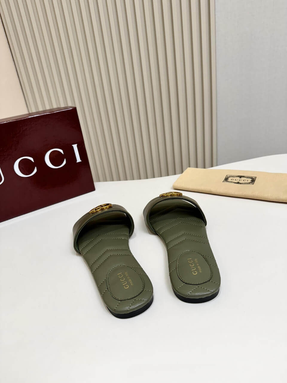 a pair of Gucci Women's Double G slide sandal - Olive Green on a table