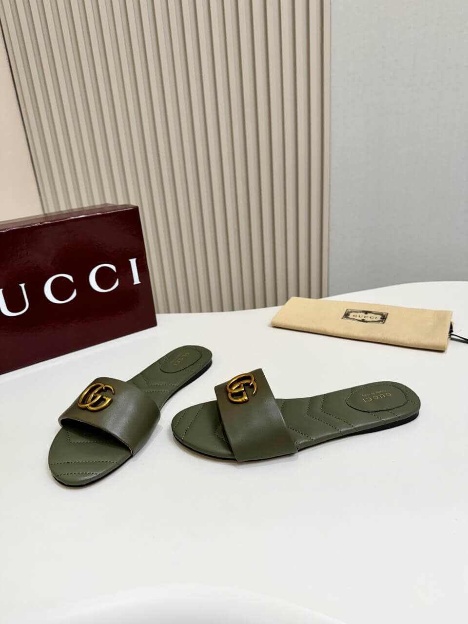 a pair of Gucci Women's Double G slide sandal - Olive Green on a table
