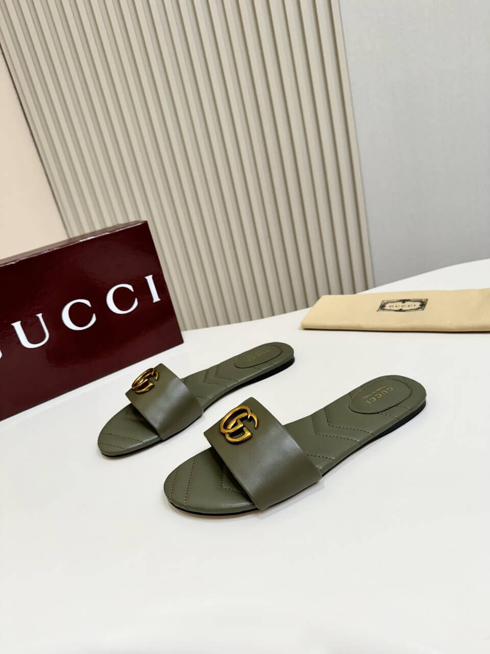 a pair of Gucci Women's Double G slide sandal - Olive Green on a table