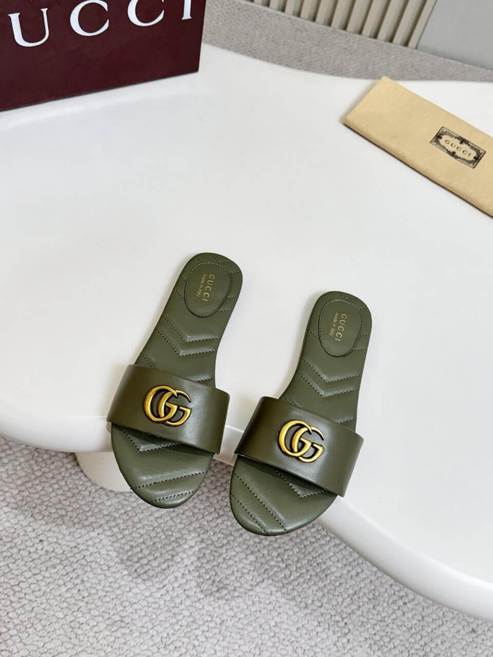 a pair of Gucci Women's Double G slide sandal - Olive Green on a table