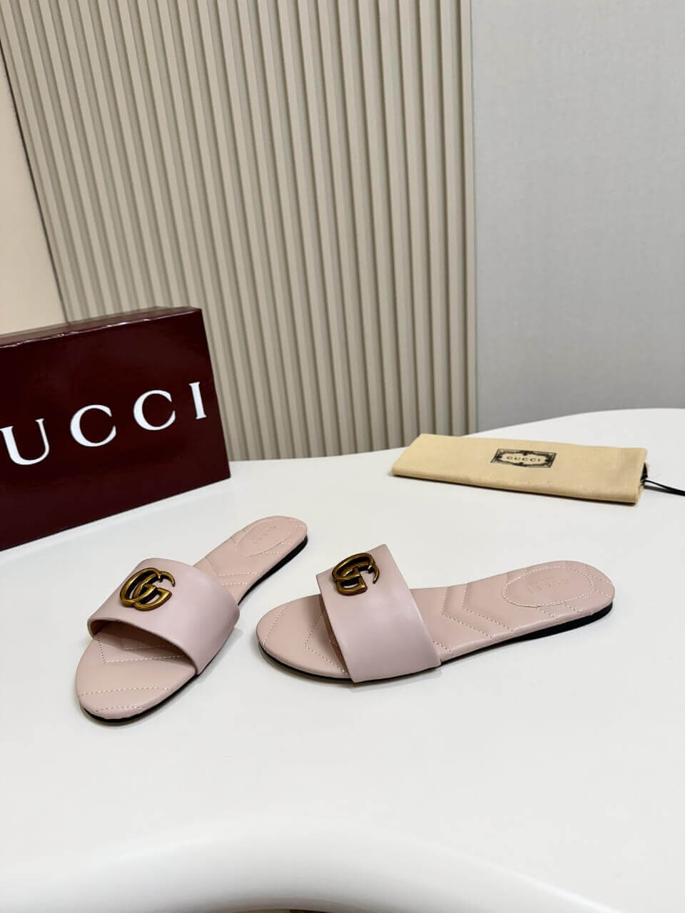 a pair of Gucci Women's Double G slide sandal - Pink on a white table