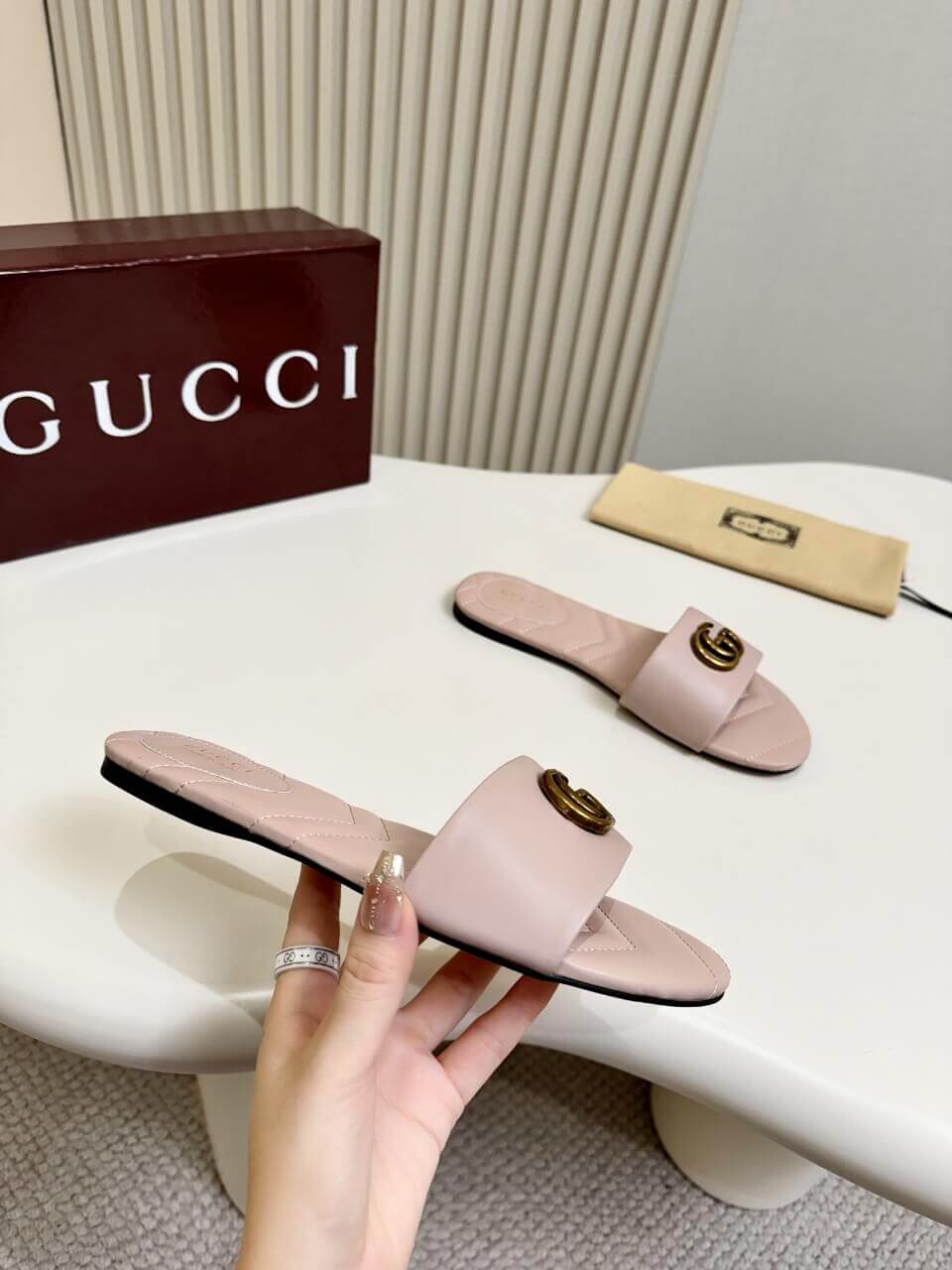 a pair of Gucci Women's Double G slide sandal - Pink on a white table