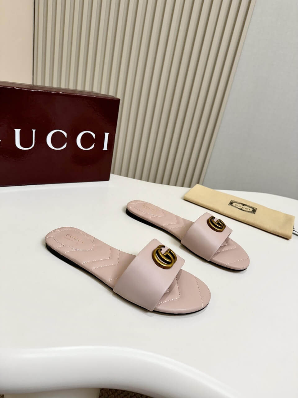 a pair of Gucci Women's Double G slide sandal - Pink on a white table