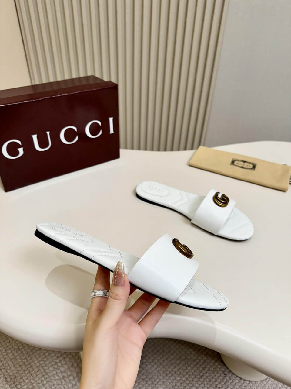 a pair of Gucci Women's Double G slide sandal - White on a table