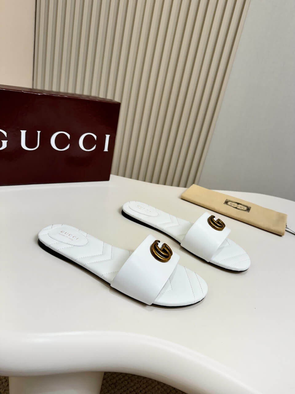 a pair of Gucci Women's Double G slide sandal - White on a table