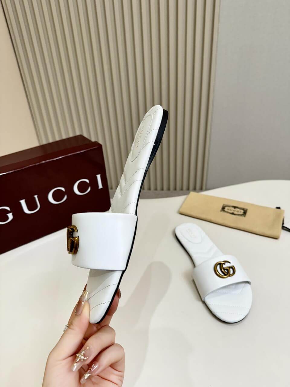 a pair of Gucci Women's Double G slide sandal - White on a table