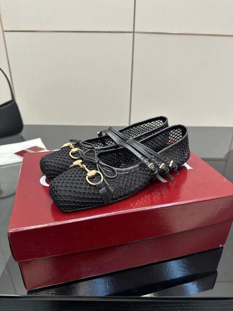 a pair of Gucci Women's Horsebit Ballet Flat - Black Mesh shoes on a red box