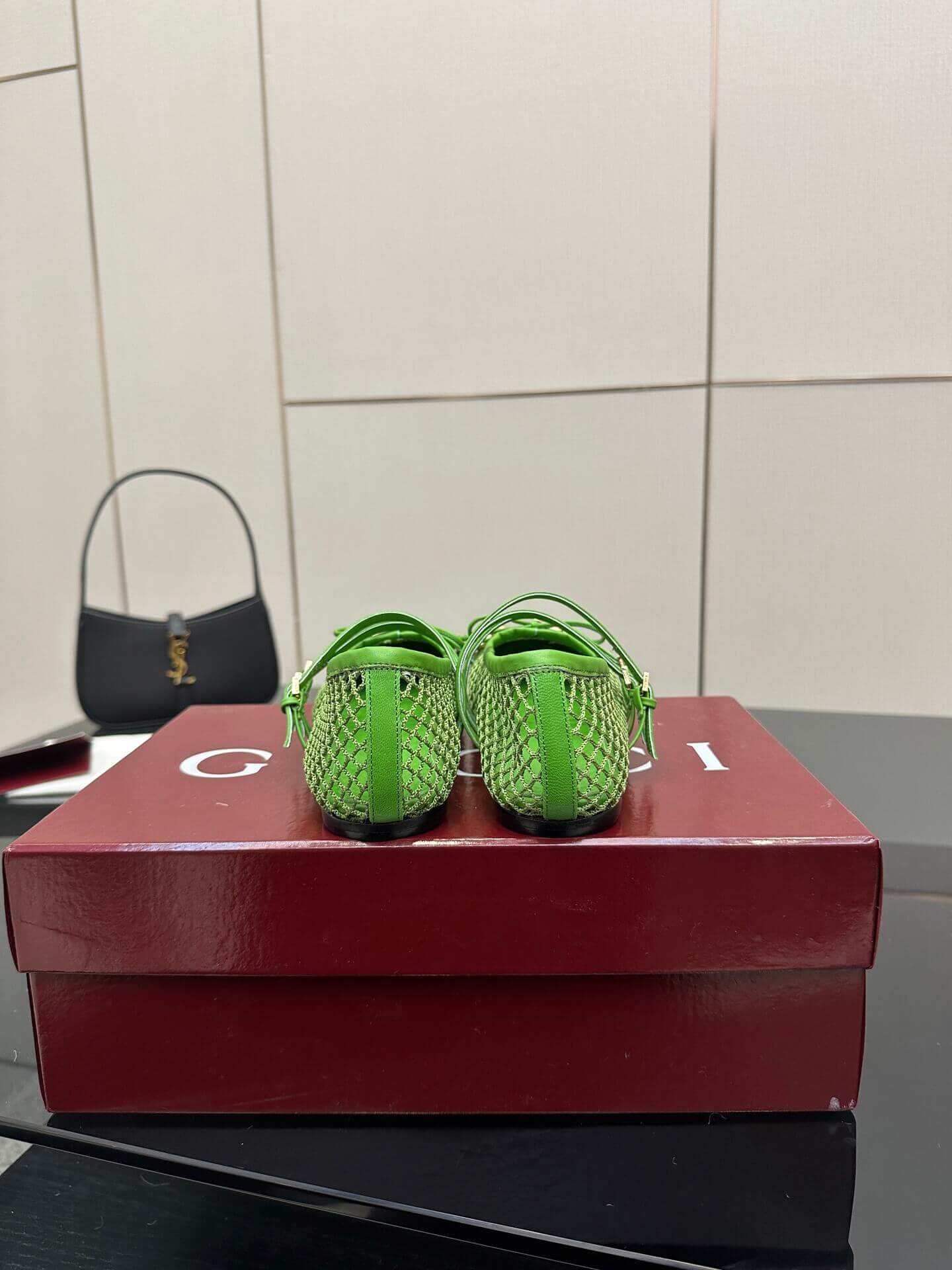 a pair of Gucci Women's Horsebit Ballet Flat - Green Mesh on a red box on a glass table