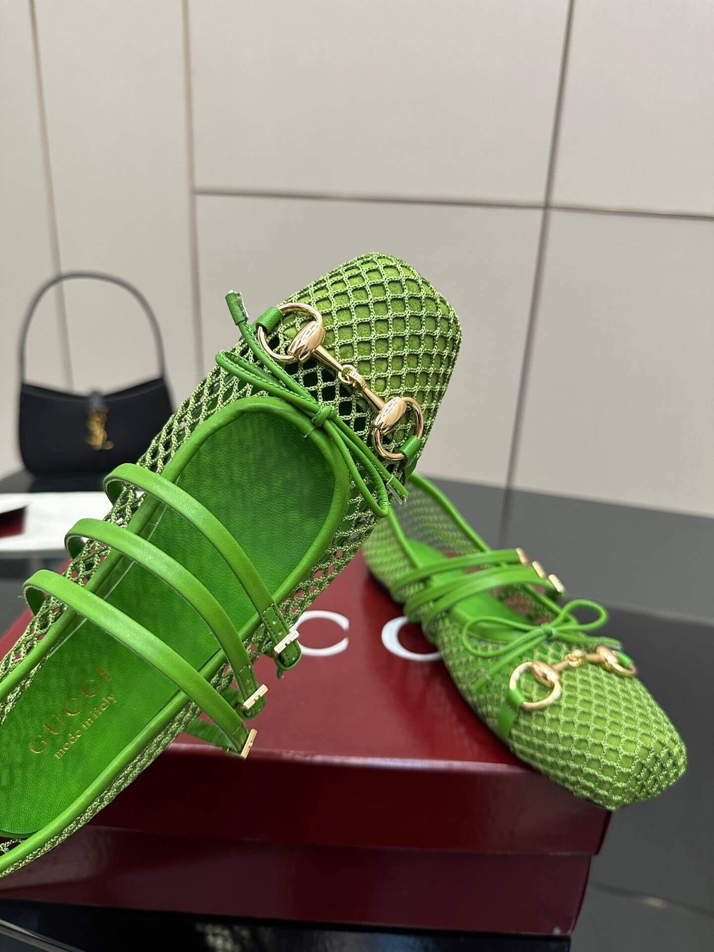 a pair of Gucci Women's Horsebit Ballet Flat - Green Mesh on a red box on a glass table