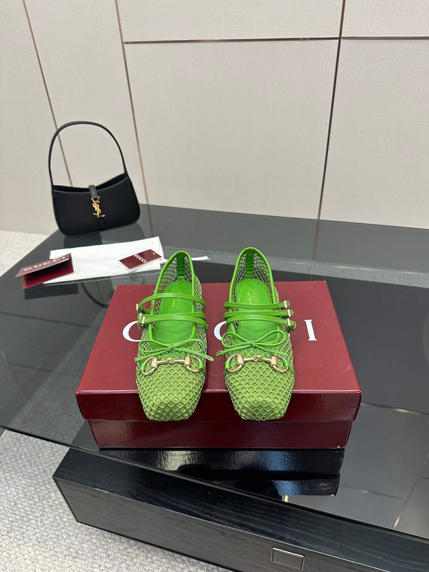 a pair of Gucci Women's Horsebit Ballet Flat - Green Mesh on a red box on a glass table