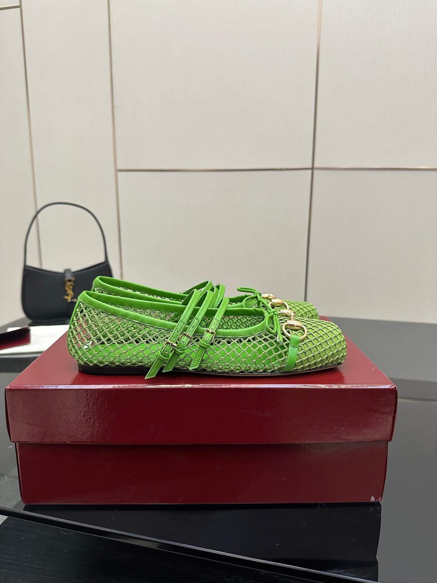 a pair of Gucci Women's Horsebit Ballet Flat - Green Mesh on a red box on a glass table
