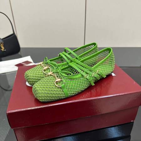 a pair of Gucci Women's Horsebit Ballet Flat - Green Mesh on a red box on a glass table