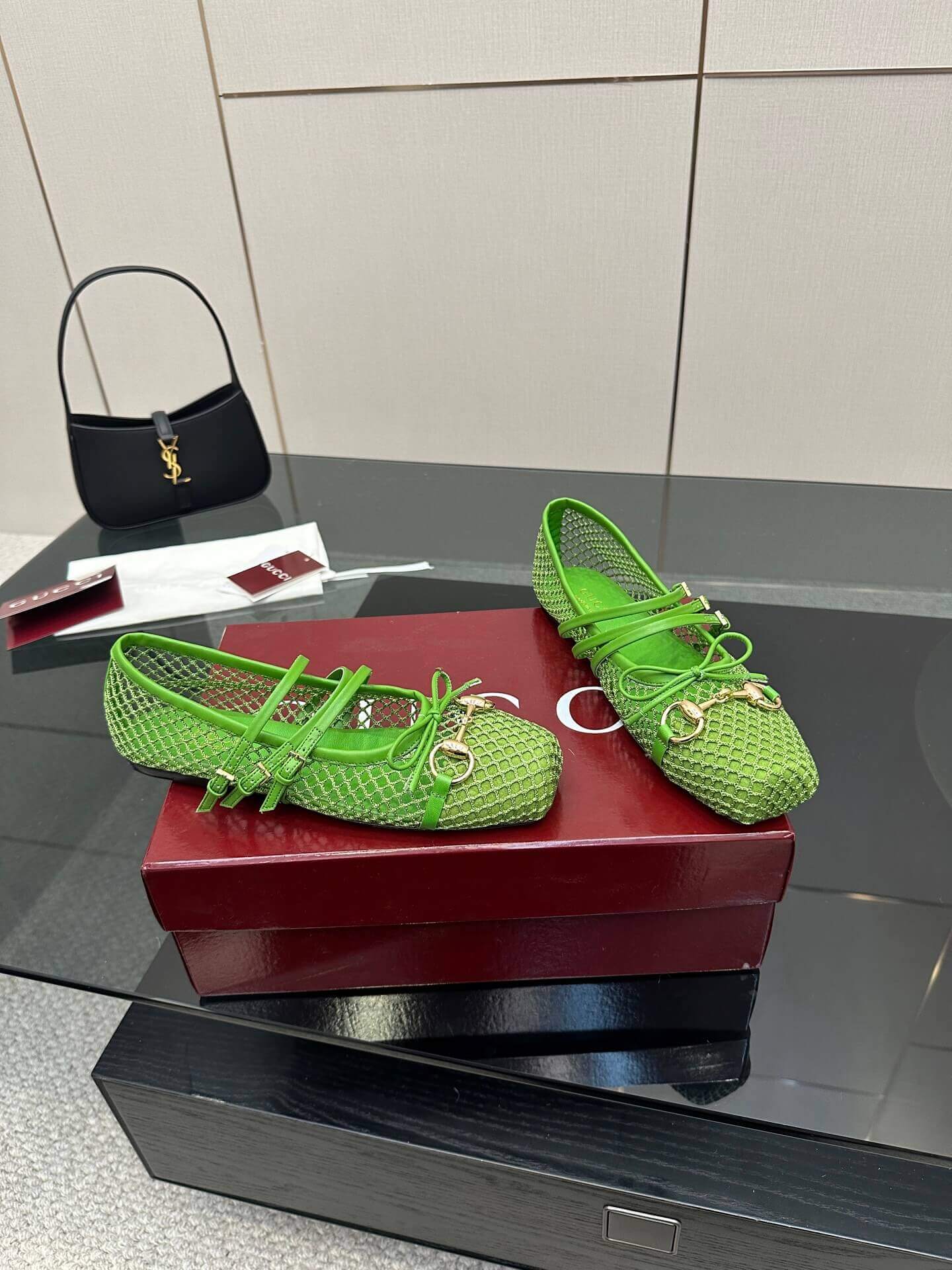a pair of Gucci Women's Horsebit Ballet Flat - Green Mesh on a red box on a glass table