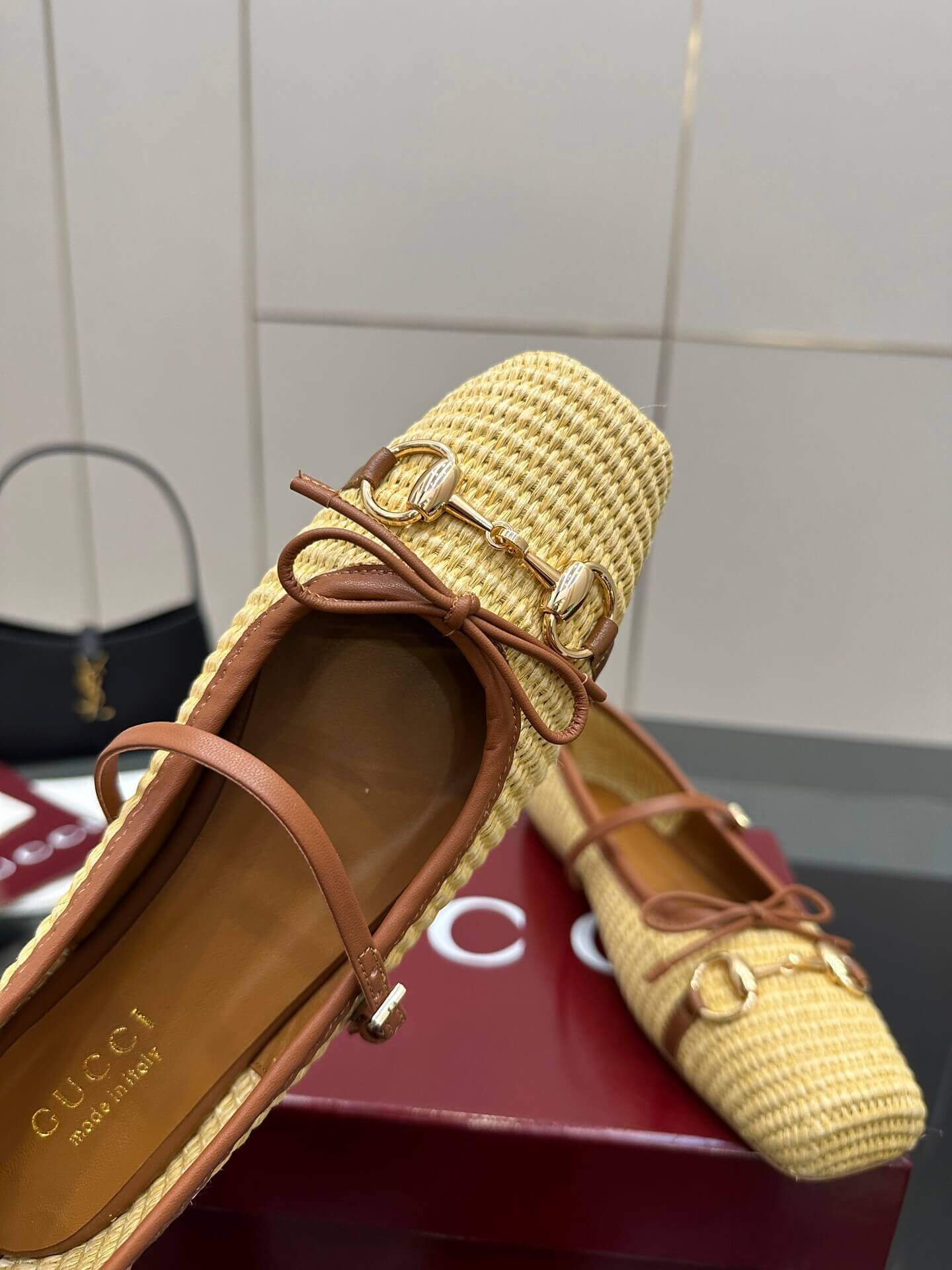a pair of Gucci Women's Horsebit Ballet Flat - Natural Raffia on a box