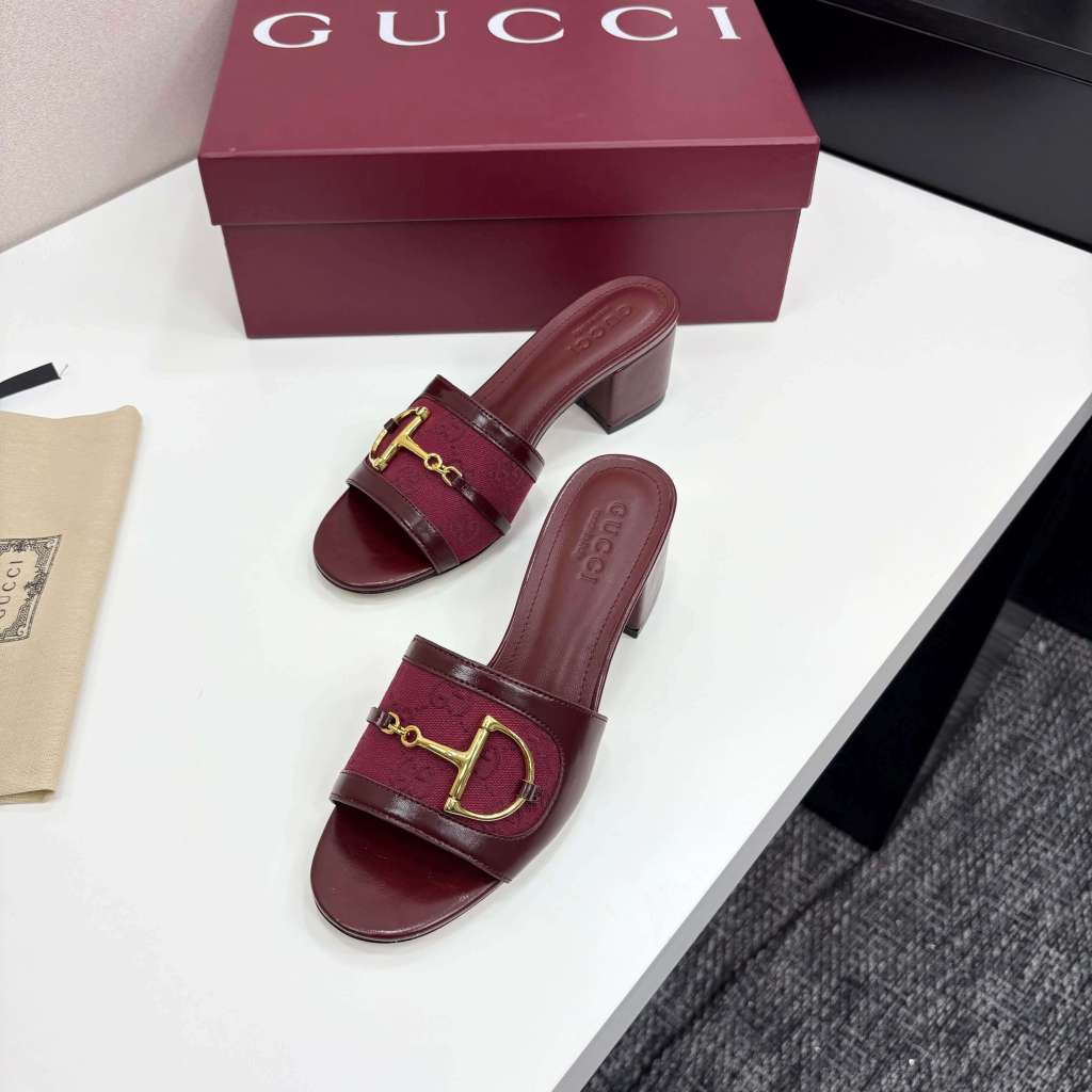 a pair of Gucci Women's Rosso Ancora Red Leather Block Heel Slide Sandals with Horsebit and GG Monogram Canvas on a white surface