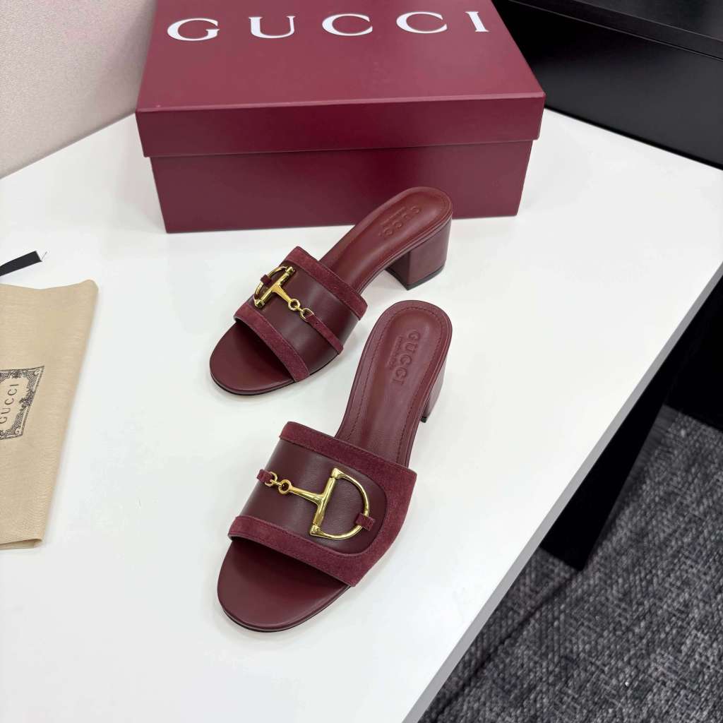 a pair of Gucci Women's Rosso Ancora Red Suede Block Heel Slide Sandals with Horsebit on a white table