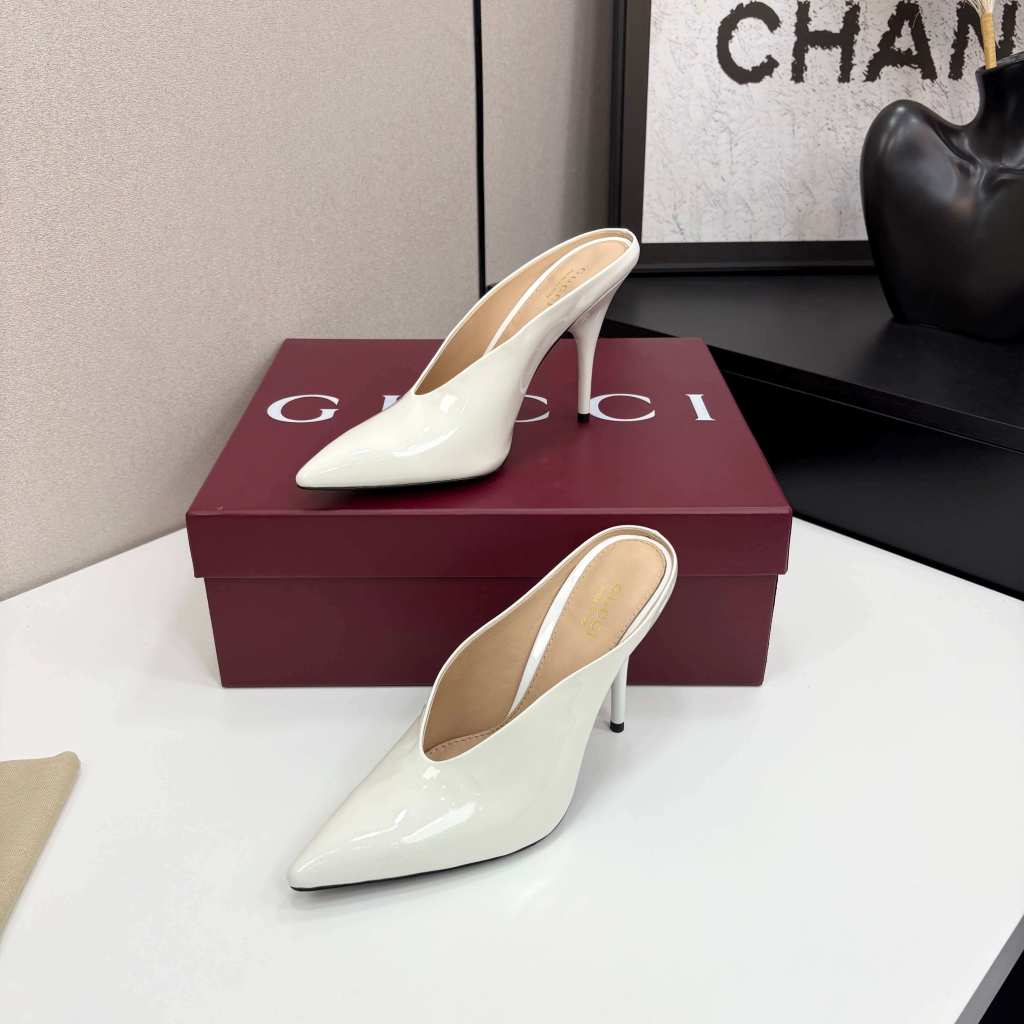 a pair of Gucci Women's White Shiny Patent Leather Pointed-Toe Stiletto Pumps on a white table