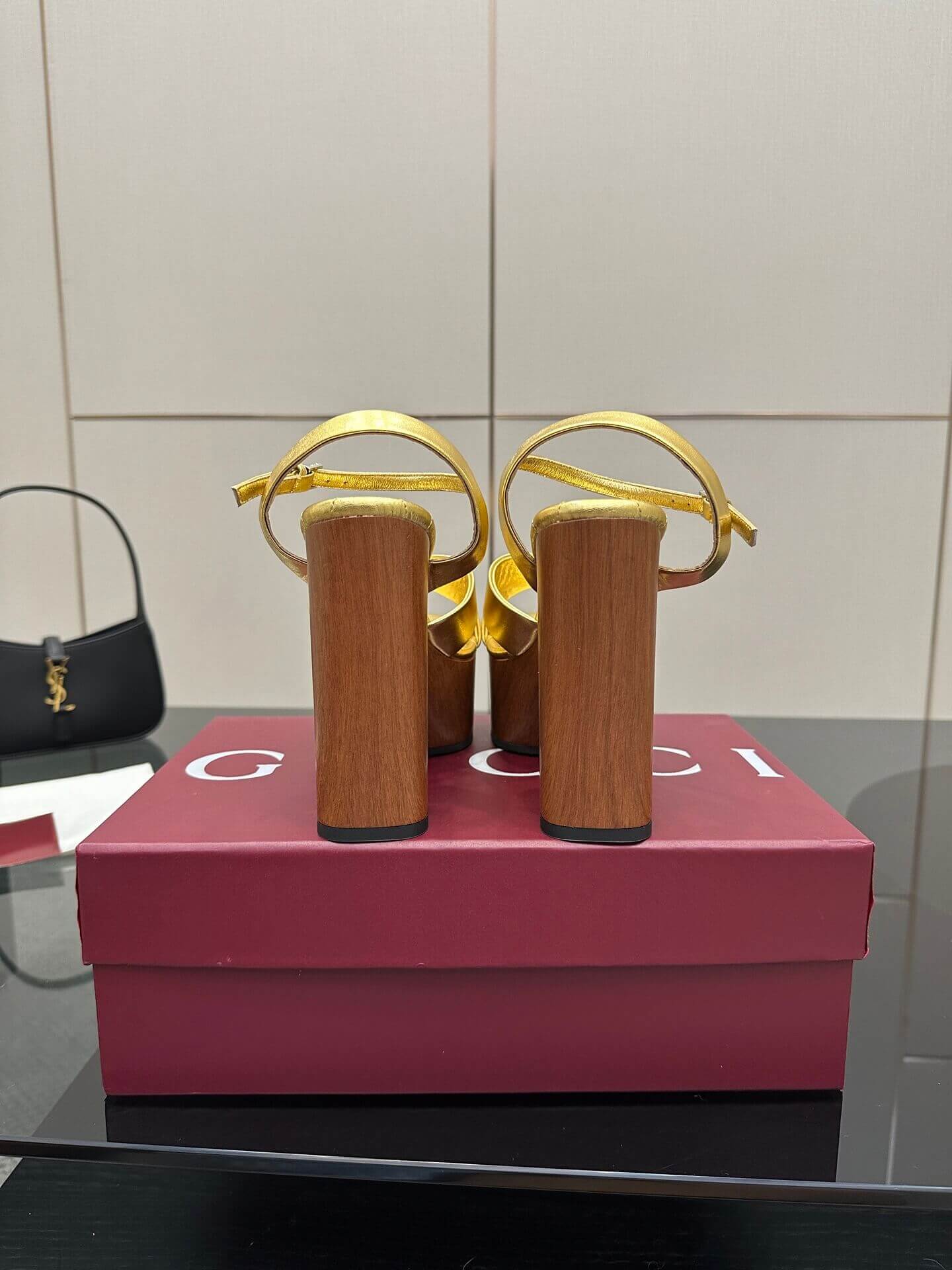 a pair of Gucci Womens platform sandal - Gold with Wooden Heel and Interlocking G Detail on a red box