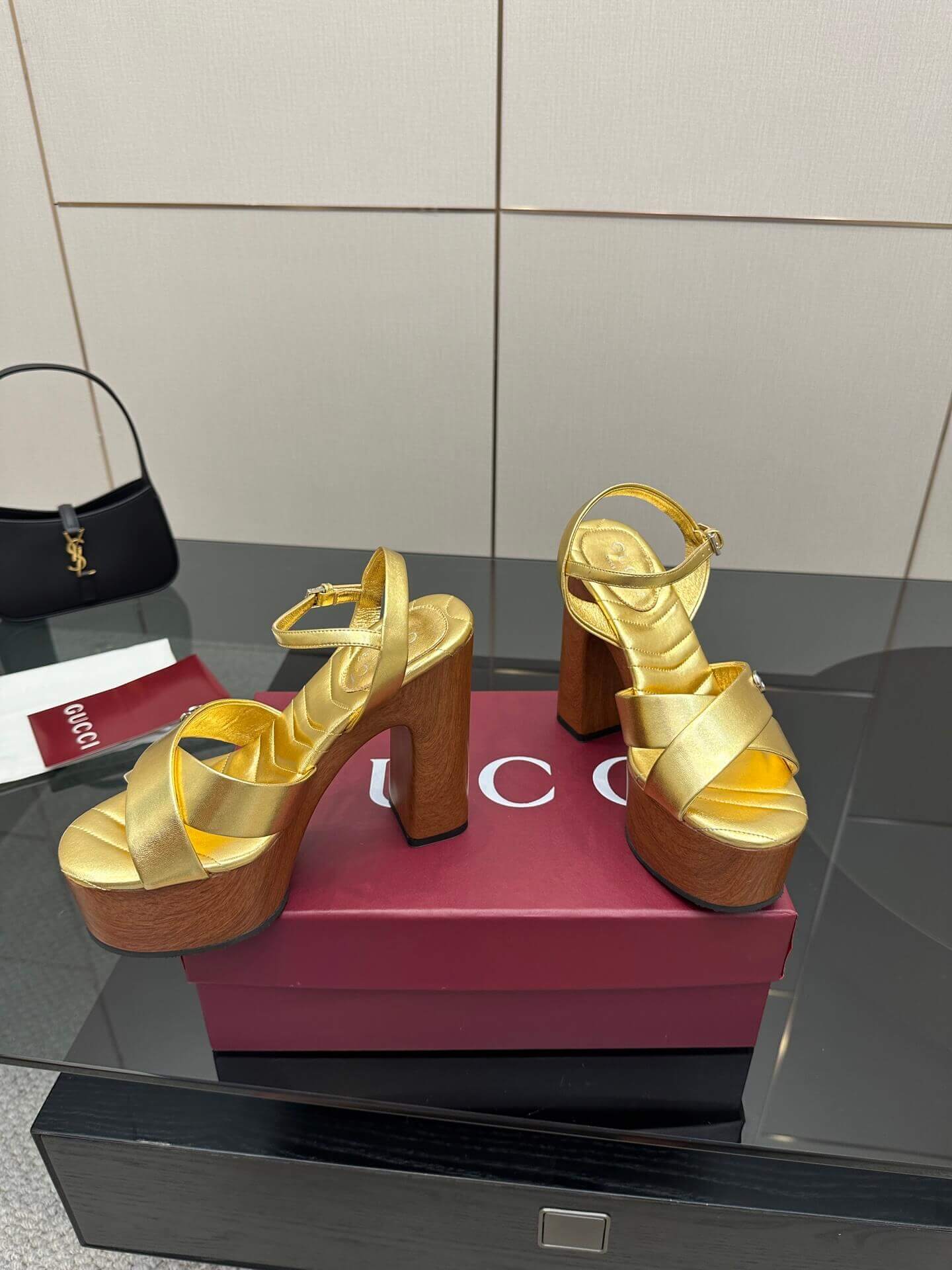 a pair of Gucci Womens platform sandal - Gold with Wooden Heel and Interlocking G Detail on a red box