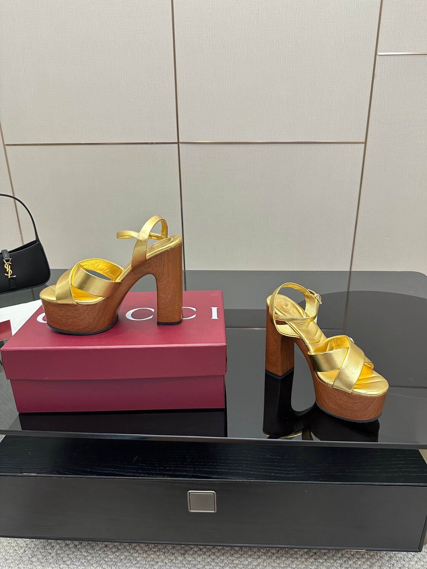 a pair of Gucci Womens platform sandal - Gold with Wooden Heel and Interlocking G Detail on a red box