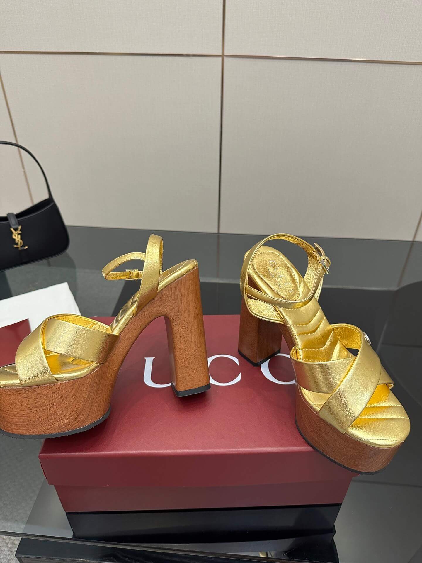 a pair of Gucci Womens platform sandal - Gold with Wooden Heel and Interlocking G Detail on a red box