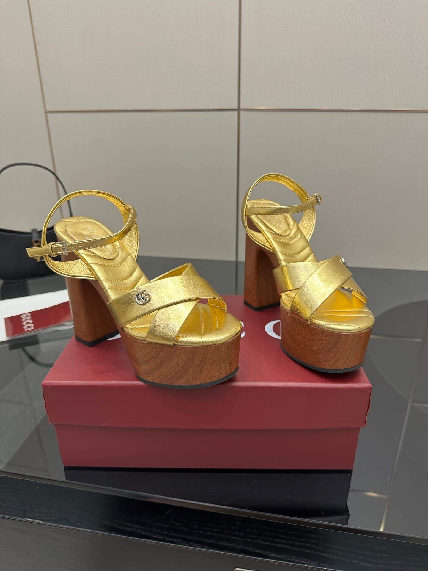 a pair of Gucci Womens platform sandal - Gold with Wooden Heel and Interlocking G Detail on a red box