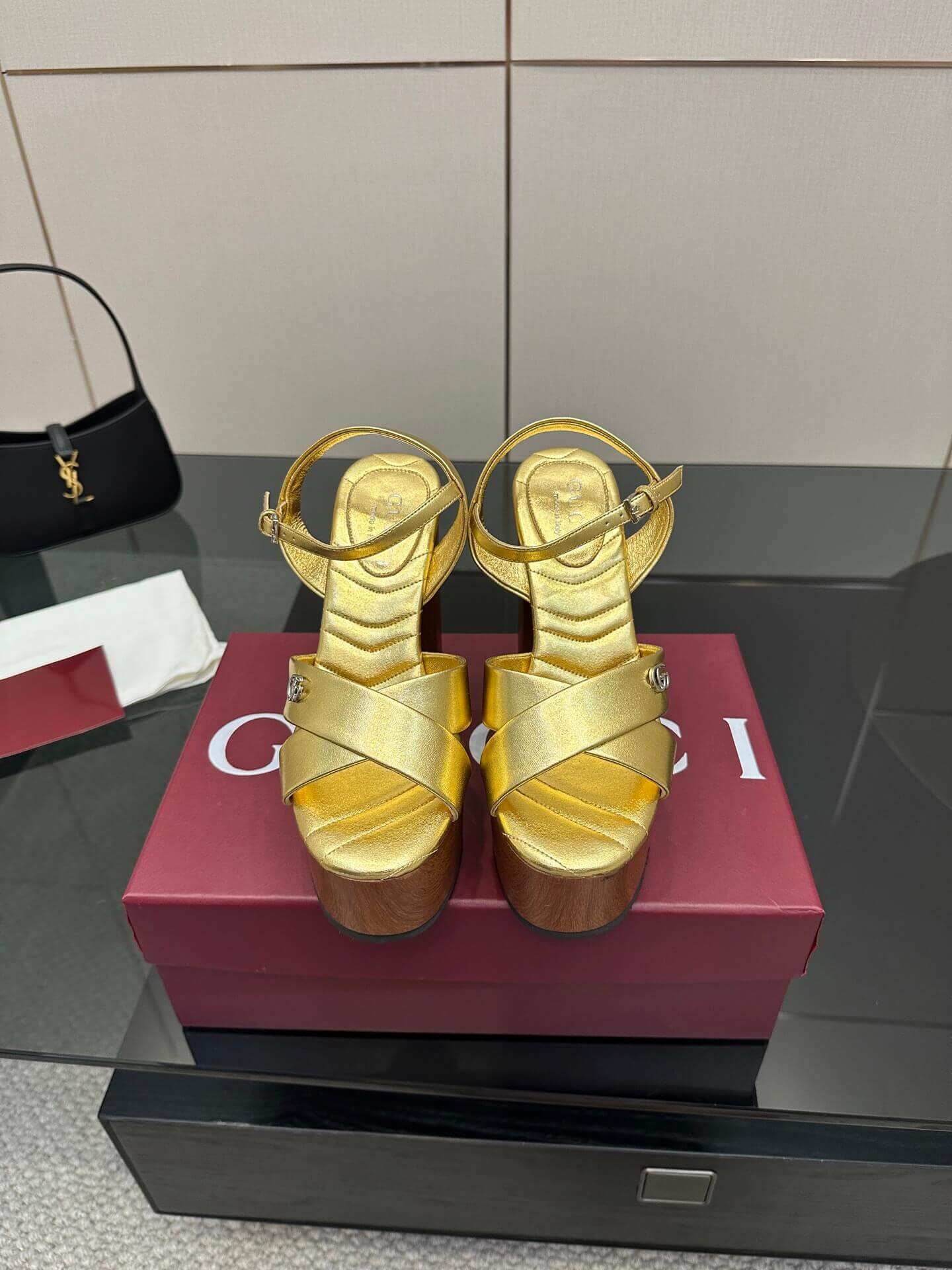 a pair of Gucci Womens platform sandal - Gold with Wooden Heel and Interlocking G Detail on a red box