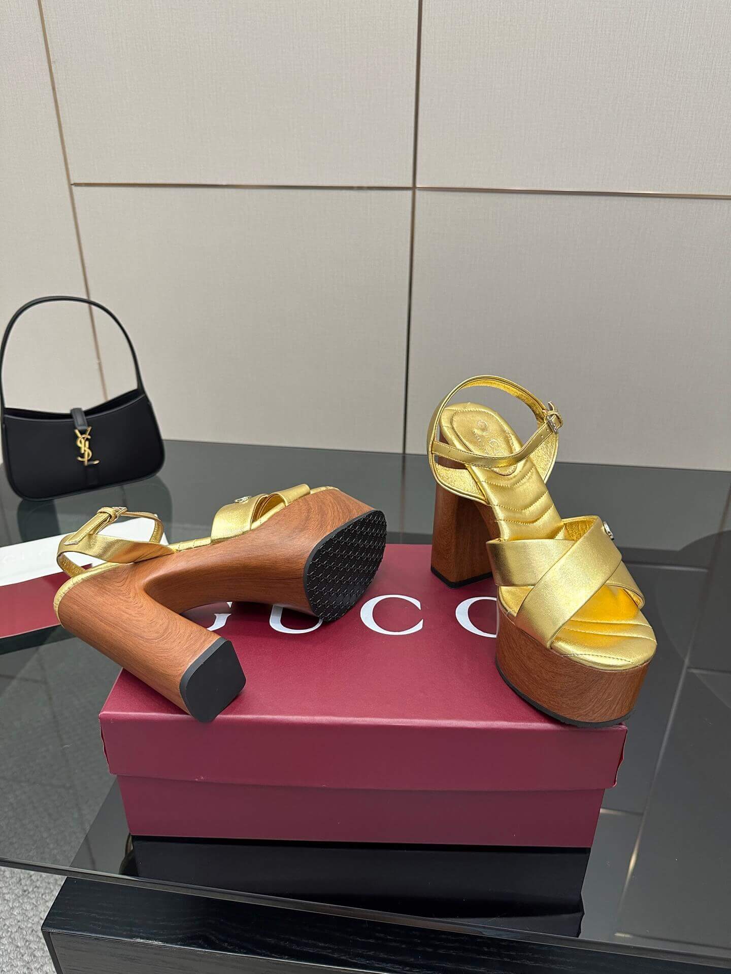 a pair of Gucci Womens platform sandal - Gold with Wooden Heel and Interlocking G Detail on a red box