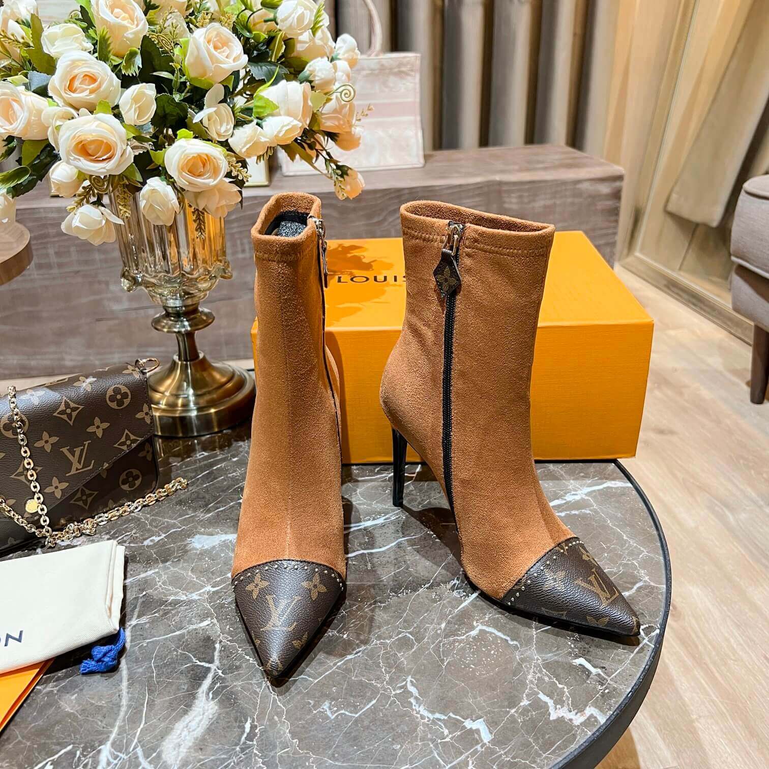 a pair of Louis Vuitton-Inspired Cherrie Ankle Boots In Tan Monogram on a table