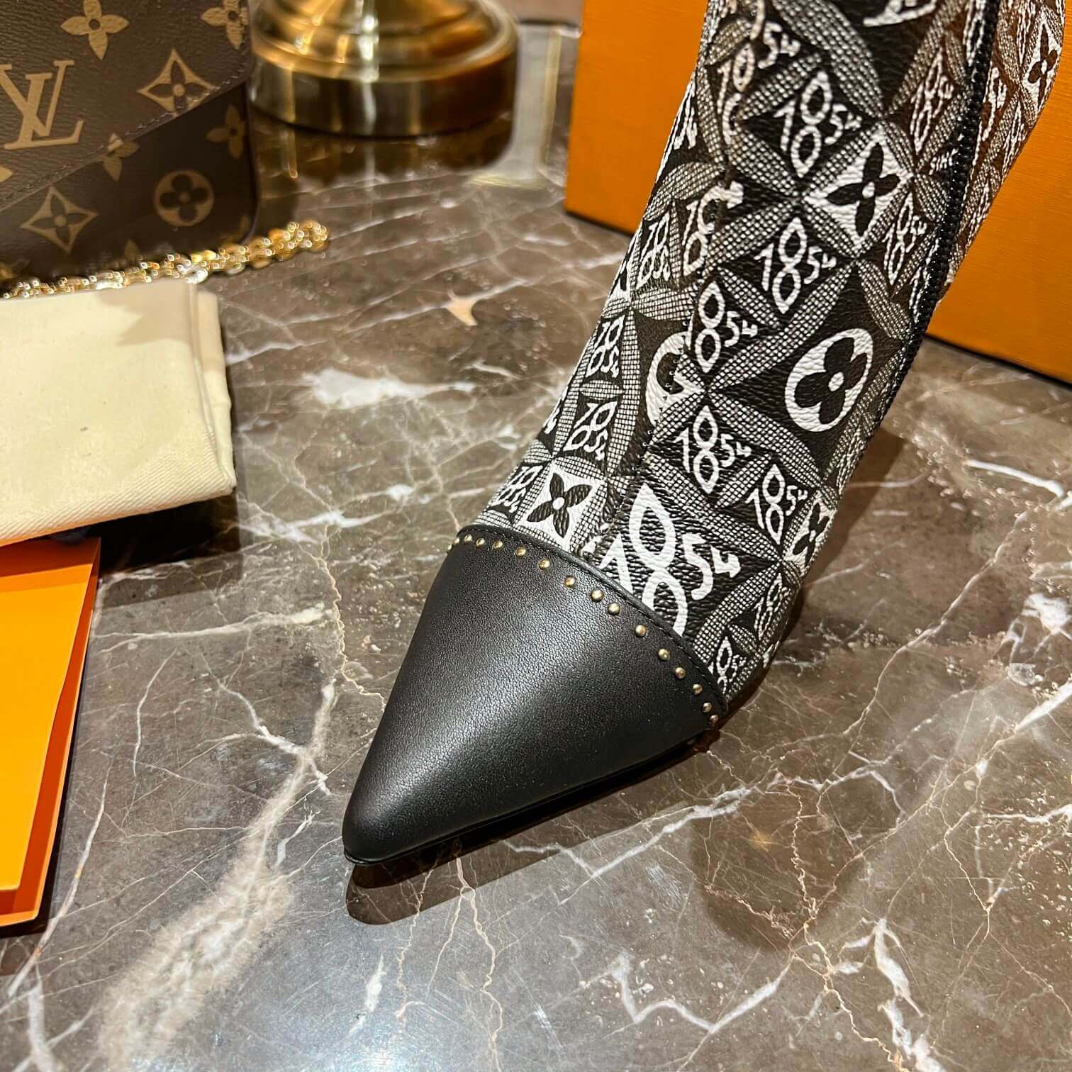 a pair of Louis Vuitton-Inspired Cherrie Ankle Boots – Monogram Noir on a table