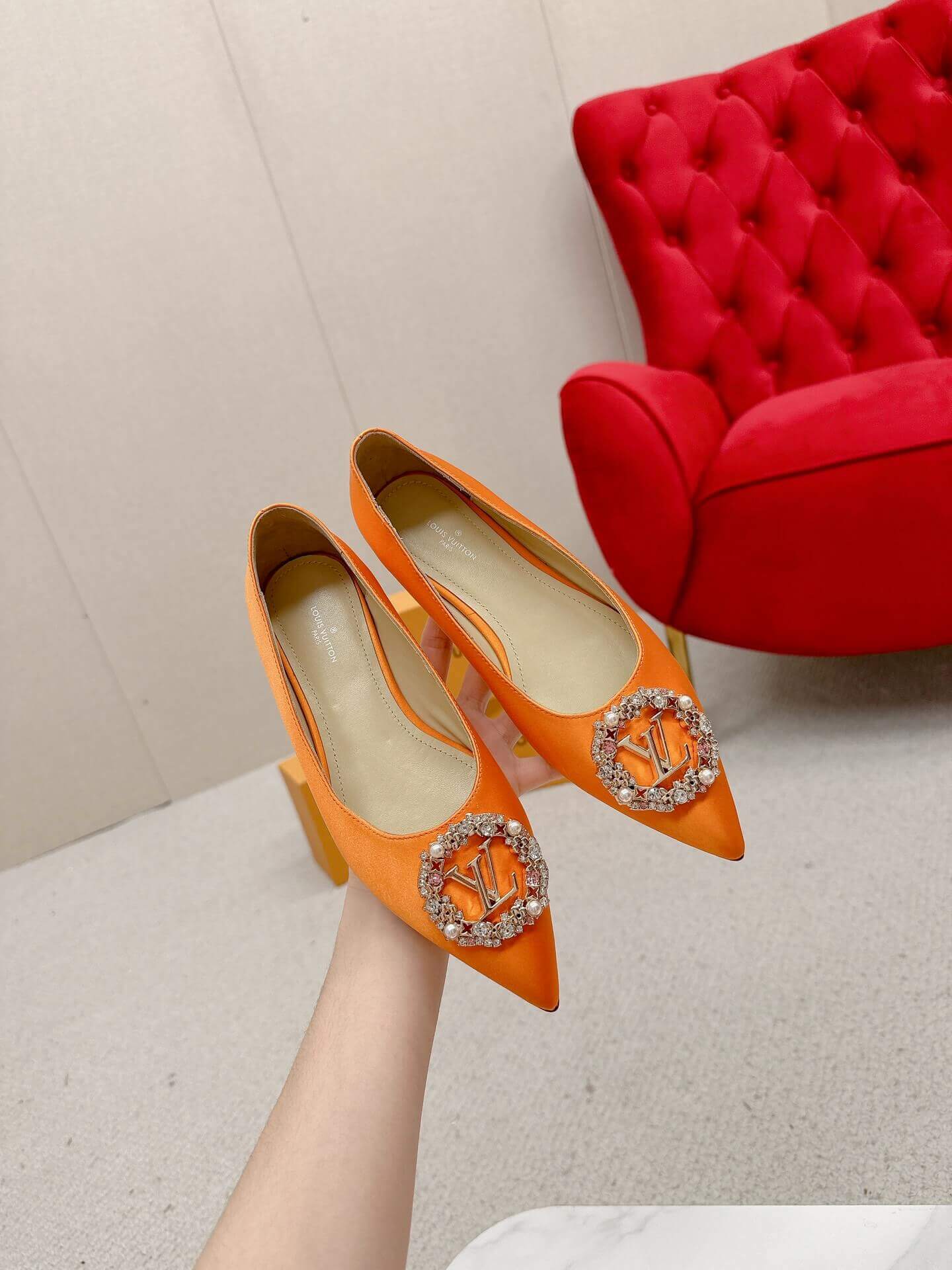 a pair of Louis Vuitton-Inspired Satin Jewel Flats – Orange on a marble