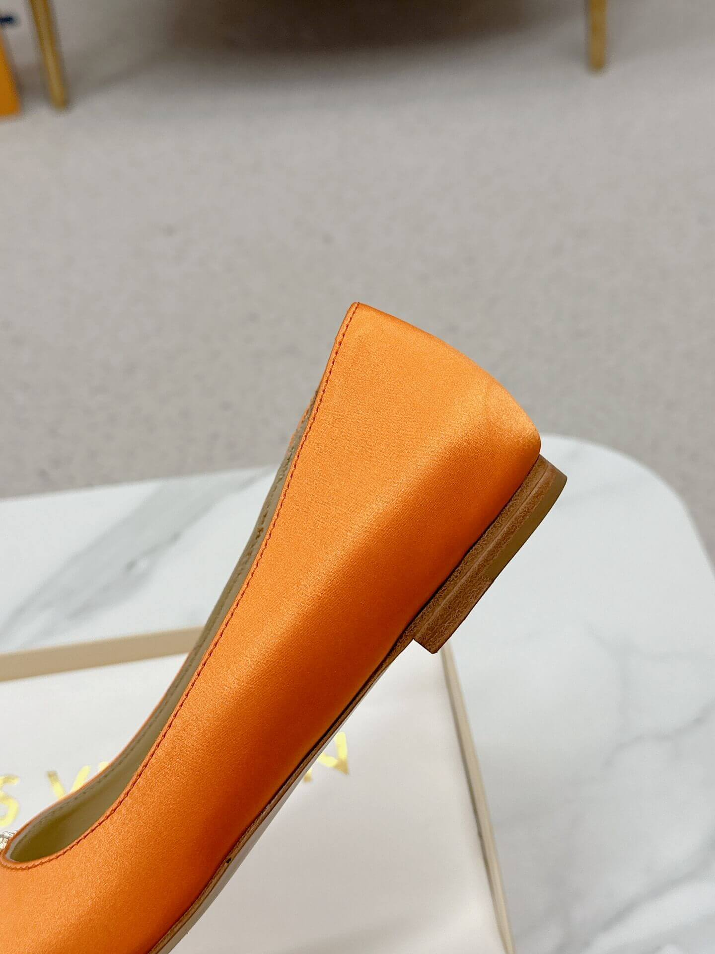 a pair of Louis Vuitton-Inspired Satin Jewel Flats – Orange on a marble