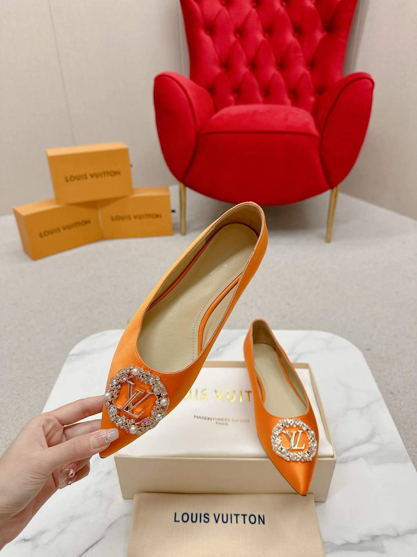 a pair of Louis Vuitton-Inspired Satin Jewel Flats – Orange on a marble