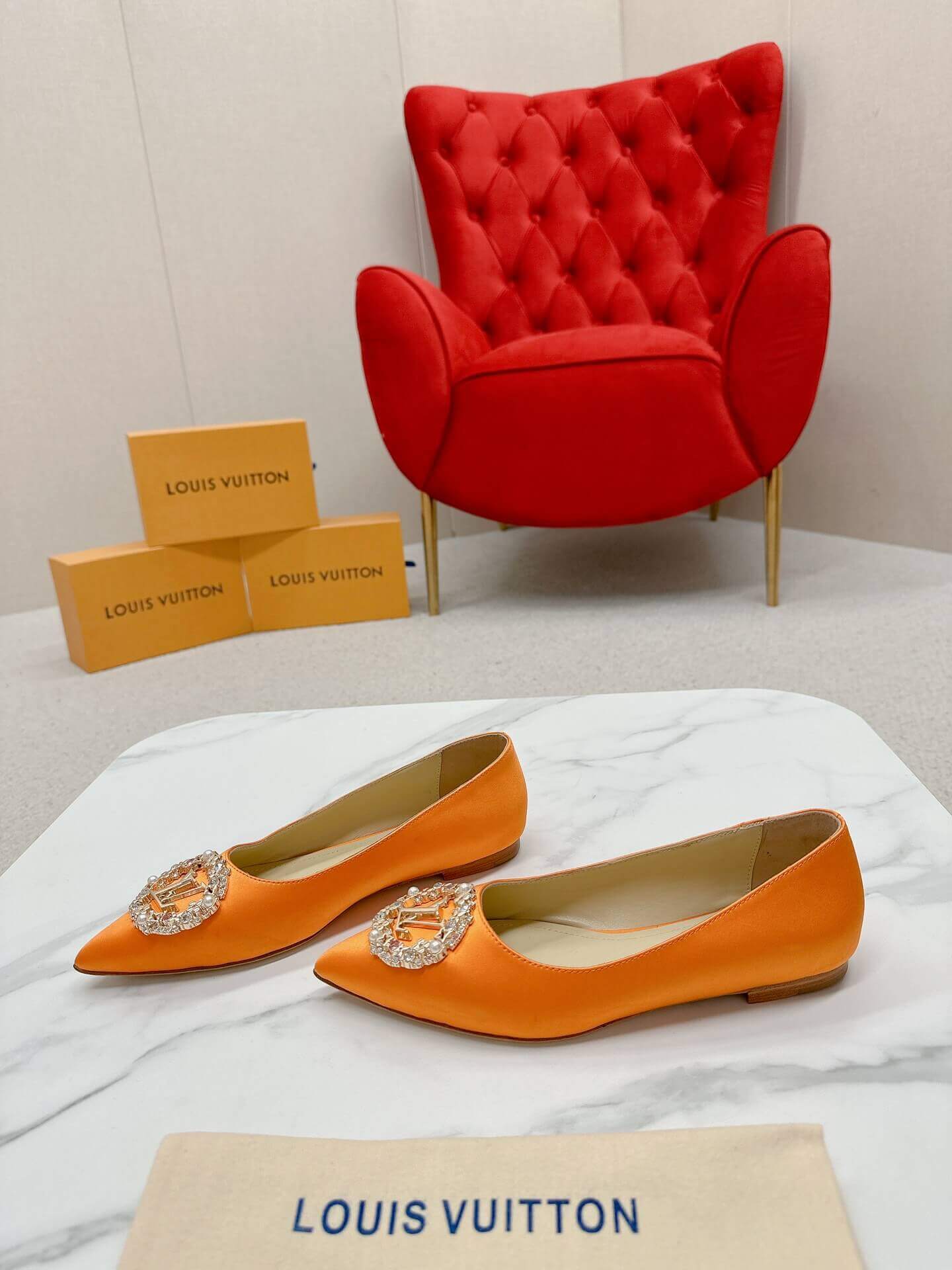 a pair of Louis Vuitton-Inspired Satin Jewel Flats – Orange on a marble table