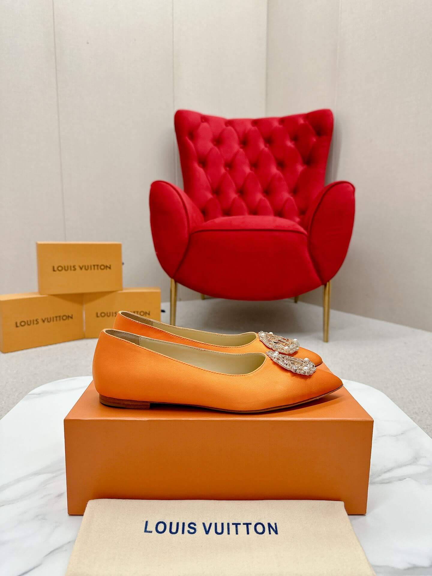 a pair of Louis Vuitton-Inspired Satin Jewel Flats – Orange on a marble