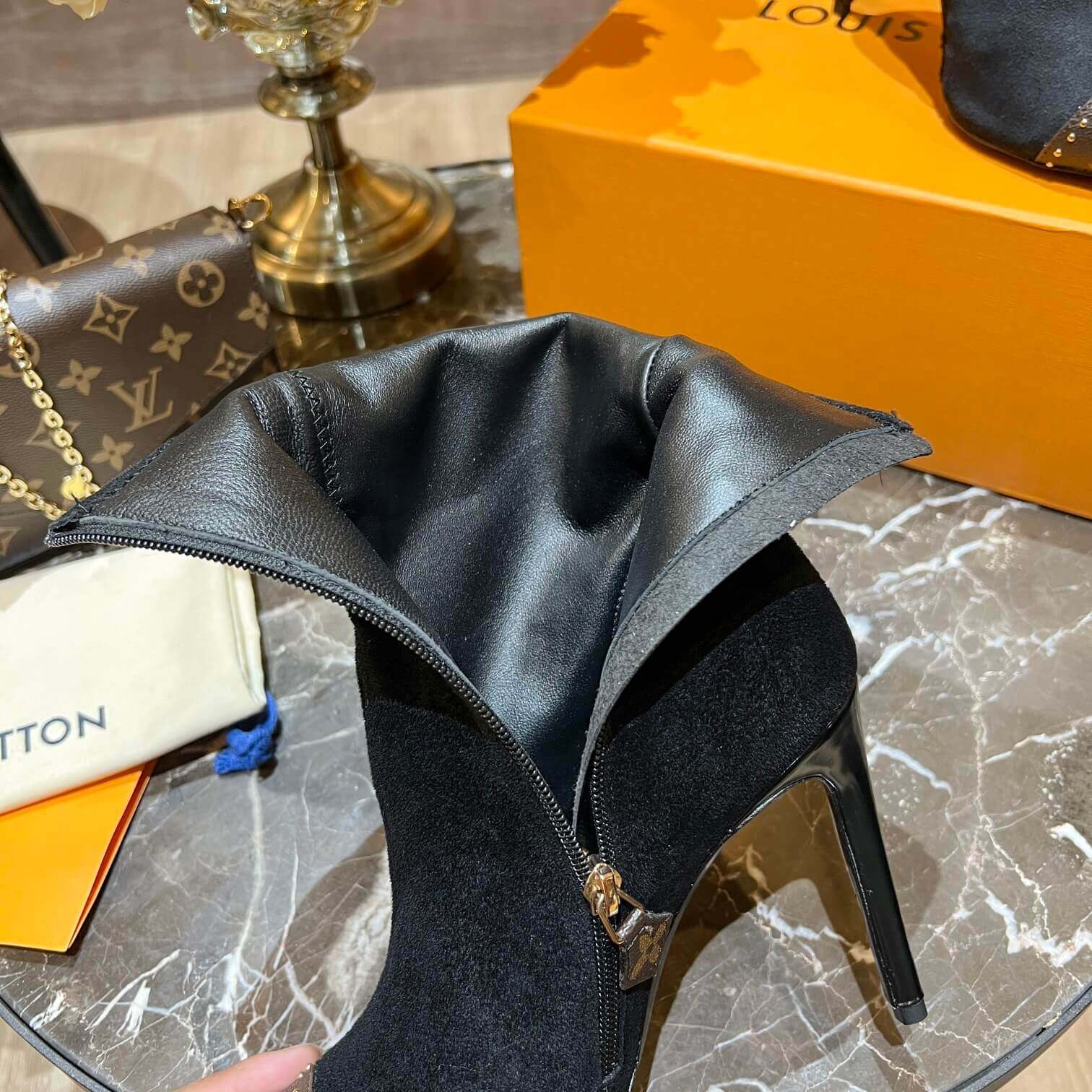 a pair of Louis Vuitton Cherie Ankle Boots in Black Leather on a marble table