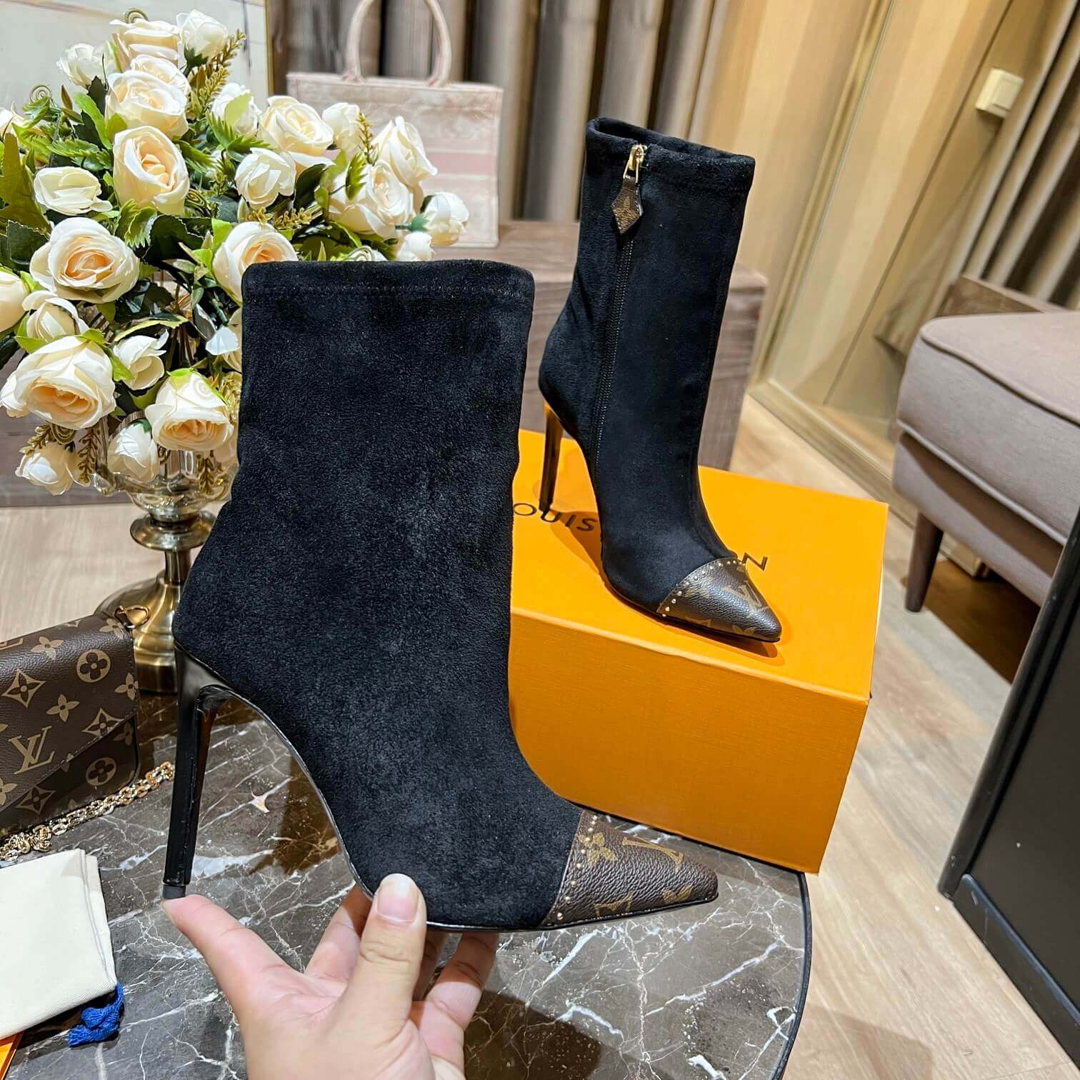 a pair of Louis Vuitton Cherie Ankle Boots in Black Leather on a marble table