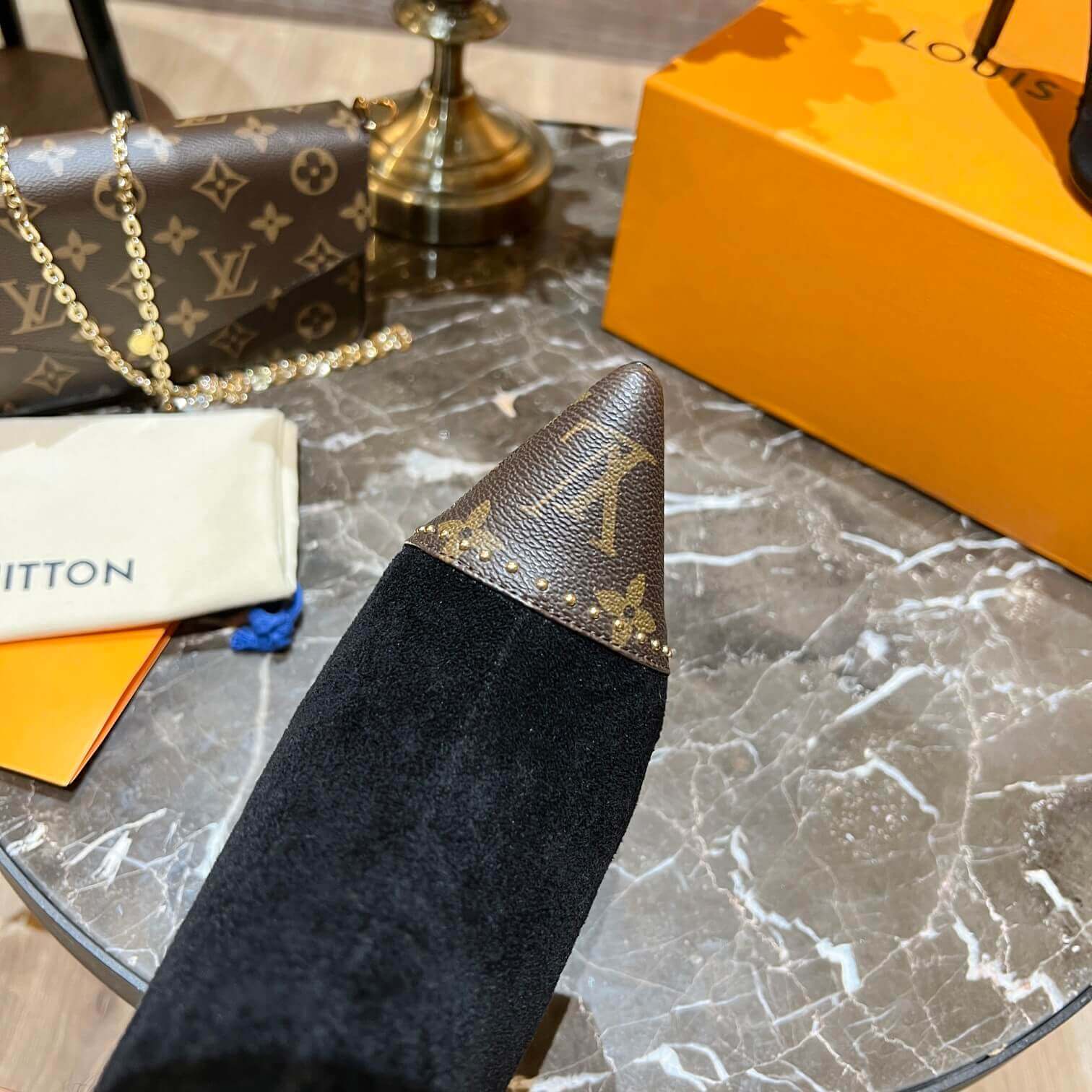 a pair of Louis Vuitton Cherie Ankle Boots in Black Leather on a marble table