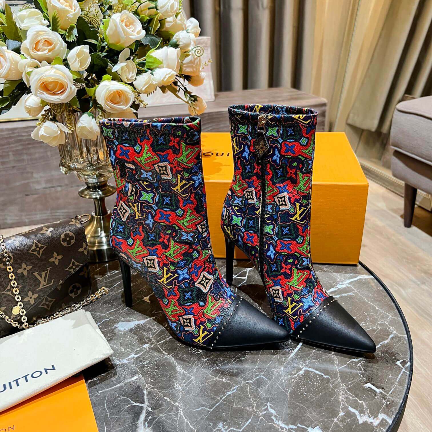 a pair of Louis Vuitton Cherrie Ankle Boots – Elegant Glossy Finish on a marble table