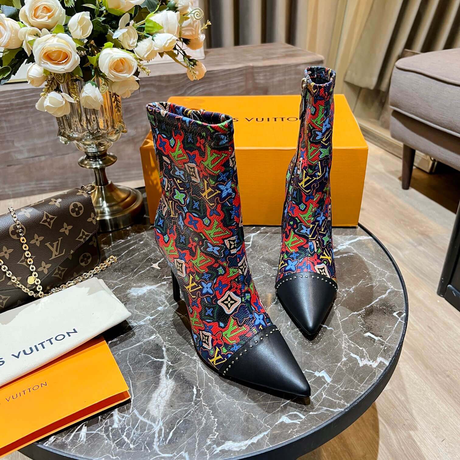 a pair of Louis Vuitton Cherrie Ankle Boots – Elegant Glossy Finish on a marble table