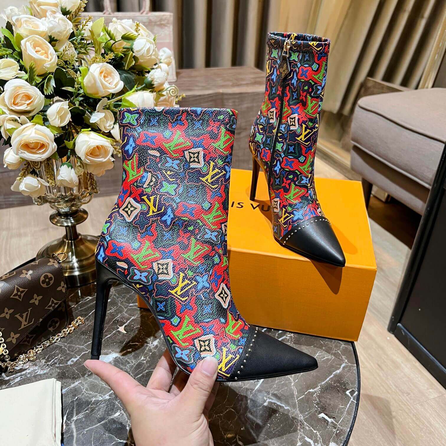 a pair of Louis Vuitton Cherrie Ankle Boots – Elegant Glossy Finish on a marble table