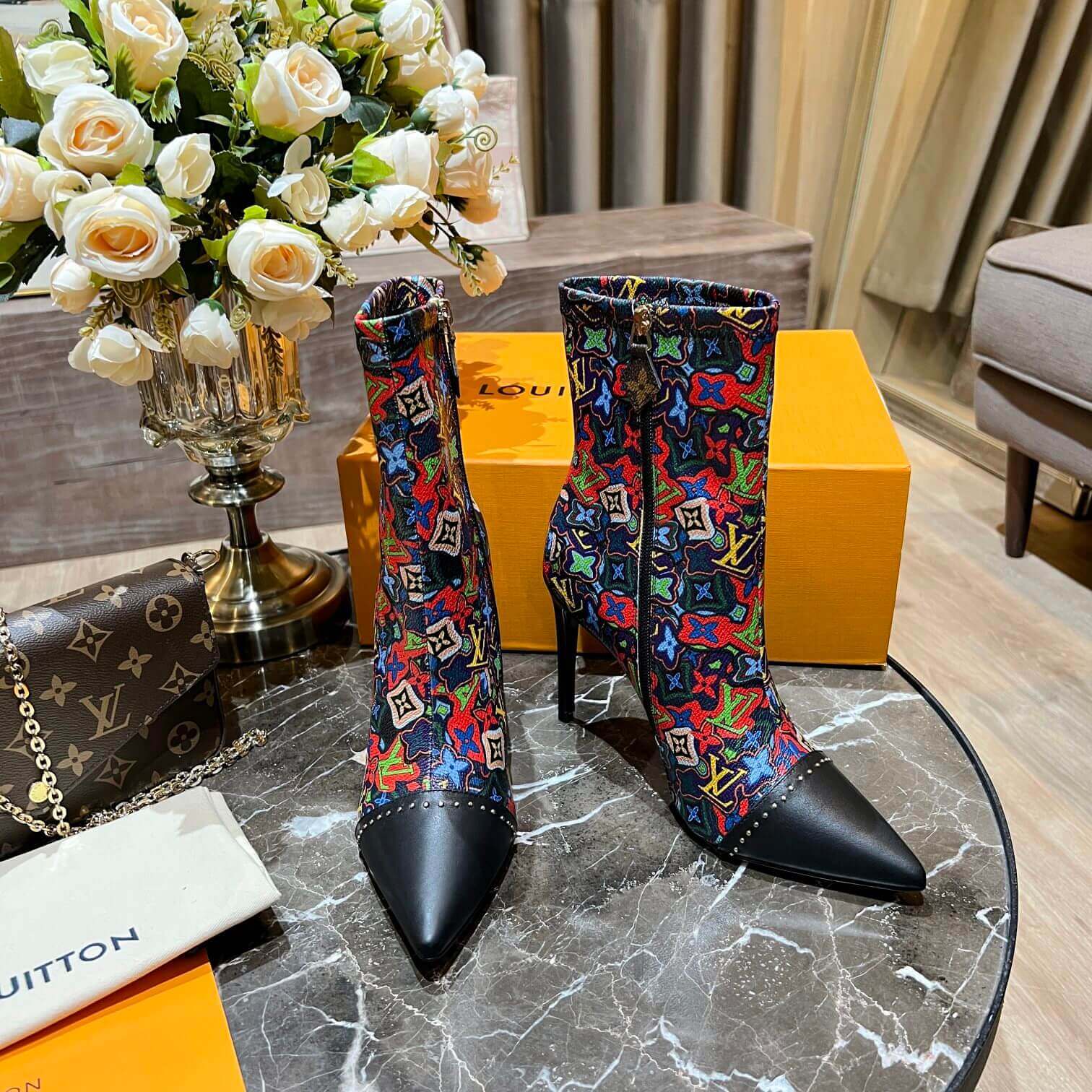a pair of Louis Vuitton Cherrie Ankle Boots – Elegant Glossy Finish on a marble table