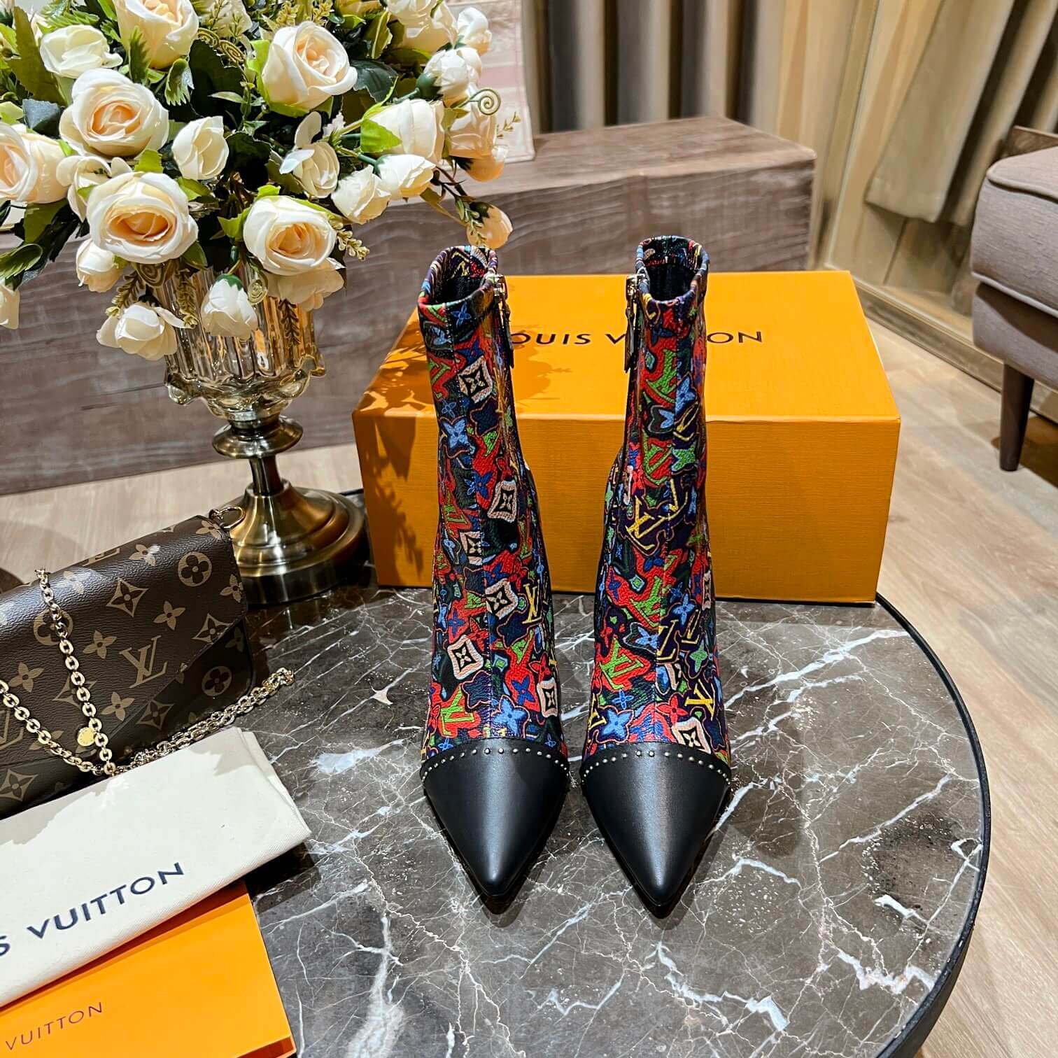 a pair of Louis Vuitton Cherrie Ankle Boots – Elegant Glossy Finish on a marble table