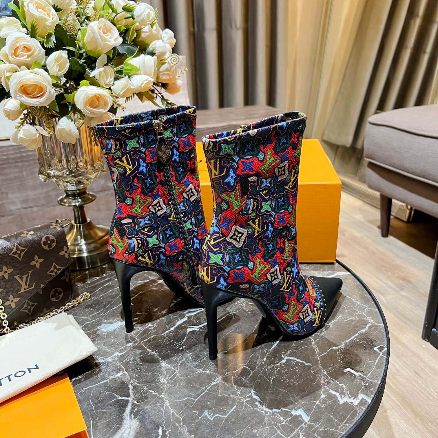 a pair of Louis Vuitton Cherrie Ankle Boots – Elegant Glossy Finish on a marble table