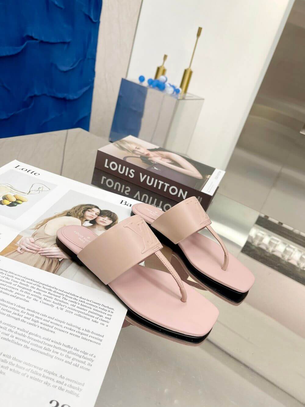 a pair of Louis Vuitton Drapy Flat Thong Sandal in Light Pink on a glass table