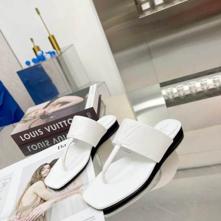 a pair of Louis Vuitton Drapy Flat Thong Sandal in White on a glass table